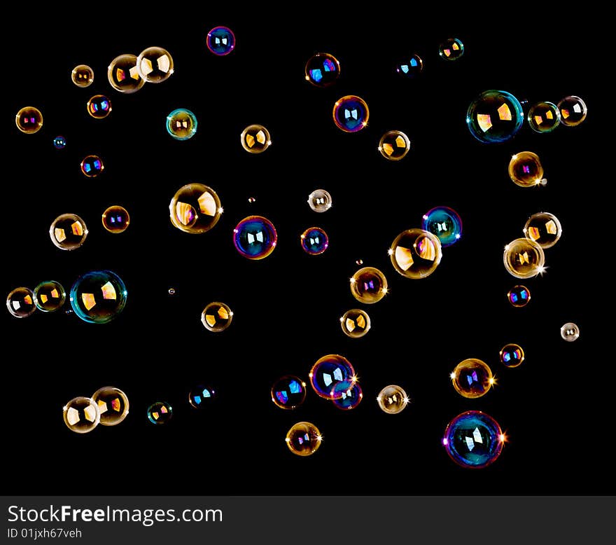 Numerous colorful soap bubbles on black background