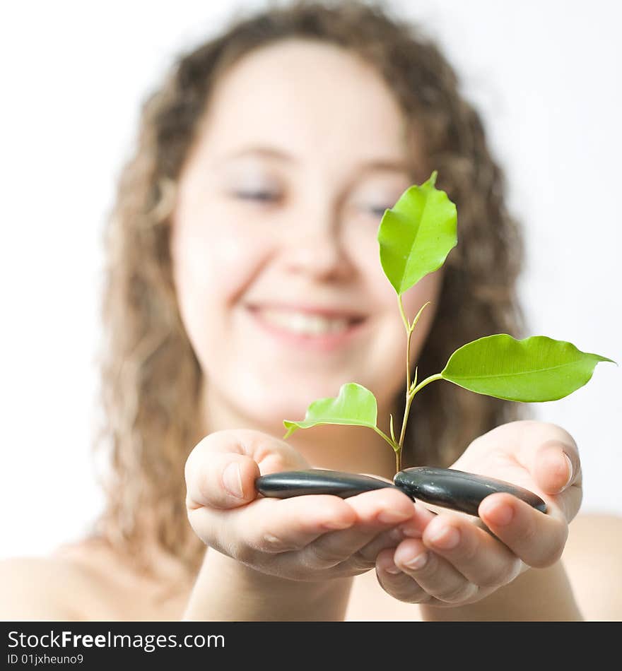 An image of a woman with green plant and stones in her hands. An image of a woman with green plant and stones in her hands