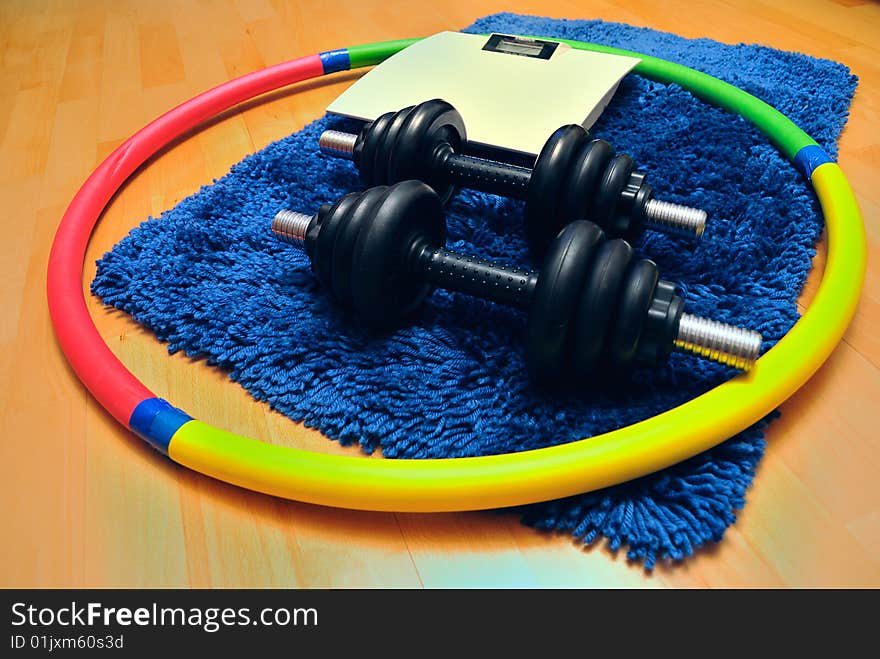 Dumbbells, hoop and scales on mat. Dumbbells, hoop and scales on mat.