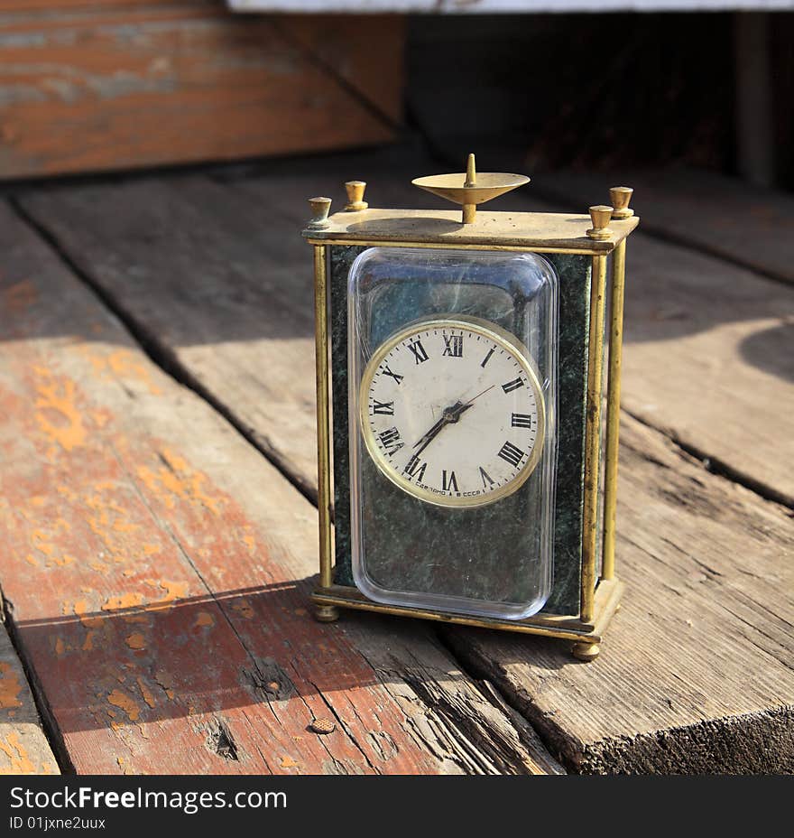 Old watch with the broken arrow on cracked wooden to a floor.