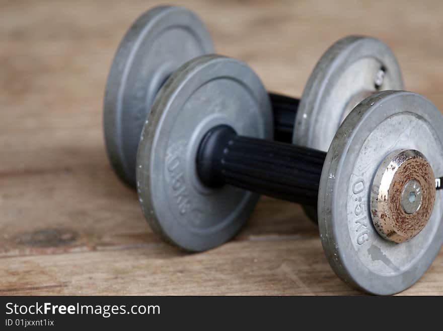 Two dumbbells lying on the wooden ground