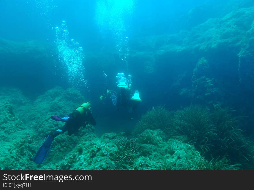 Divers in the mediterranean sea on a cave`s entrance. Divers in the mediterranean sea on a cave`s entrance.