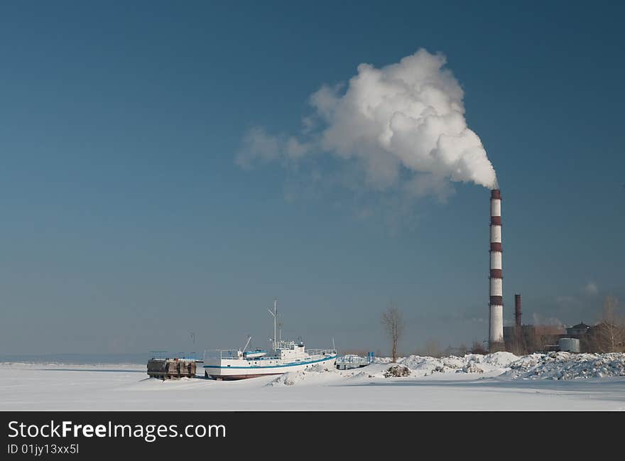 Smoking chimney over frozen lake and a ship