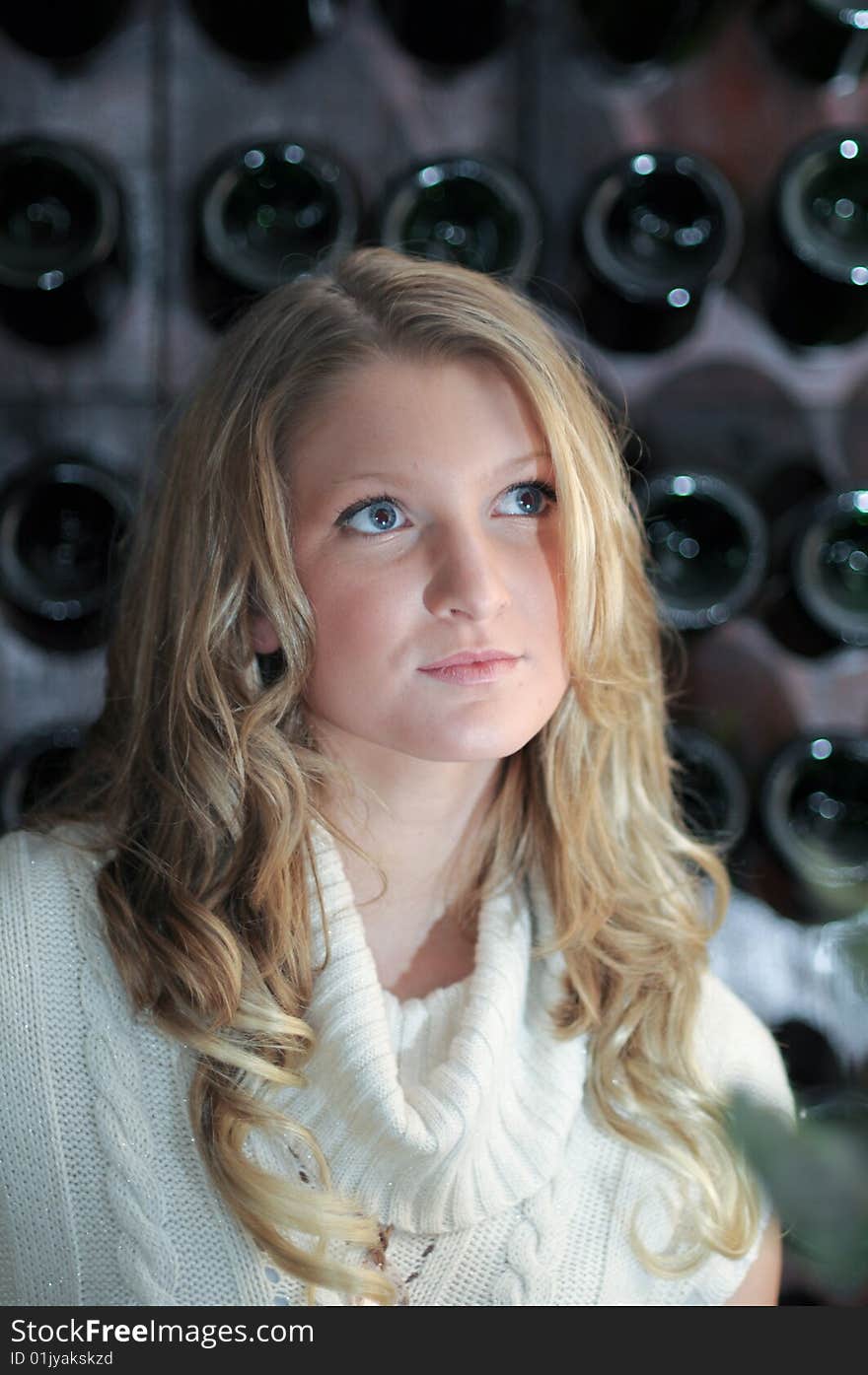 Blond girl in front of wine rack