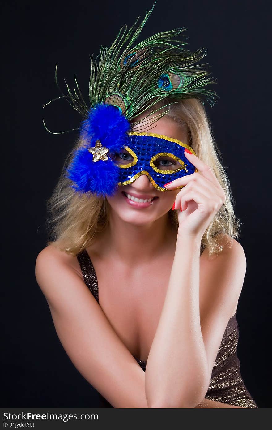 Beautiful girl in carnival mask against a dark background