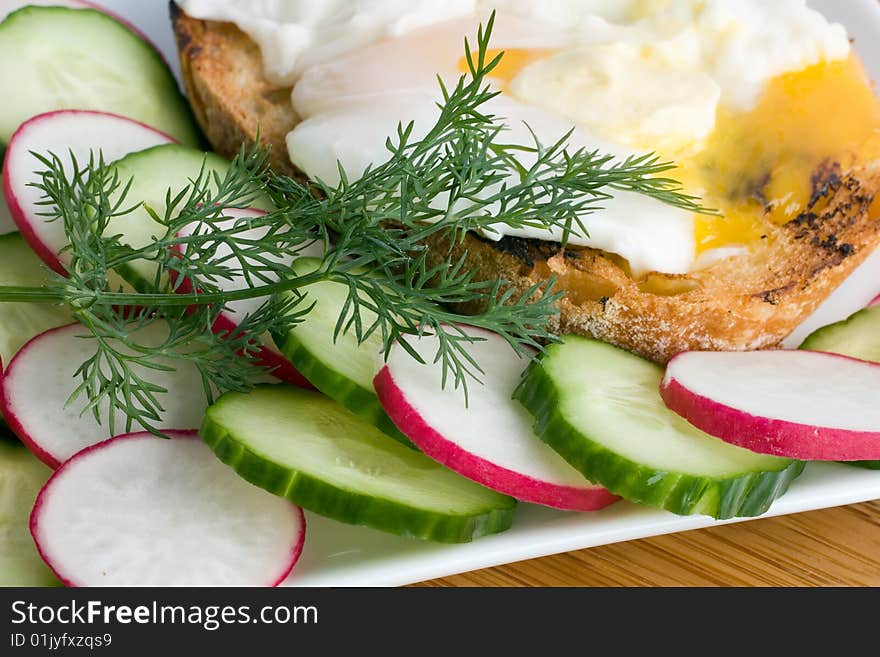 Fresh cucumber and radishes salad with egg benedict on a toast. Fresh cucumber and radishes salad with egg benedict on a toast