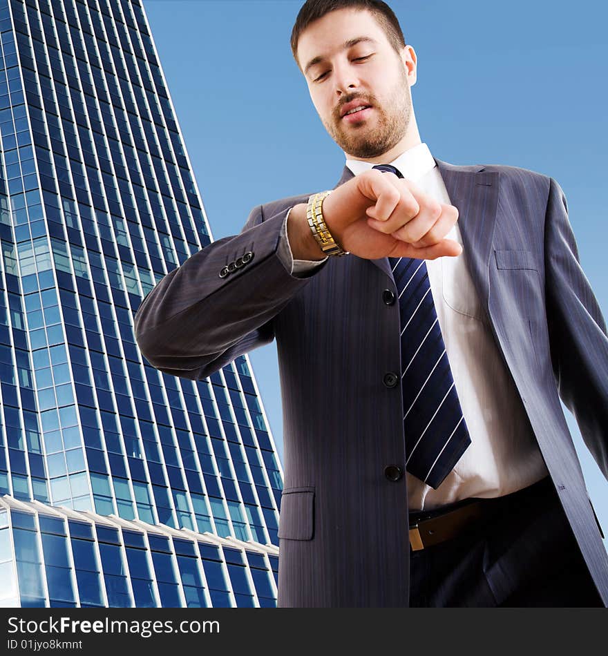 The modern businessman looking at wrist watch against a skyscraper