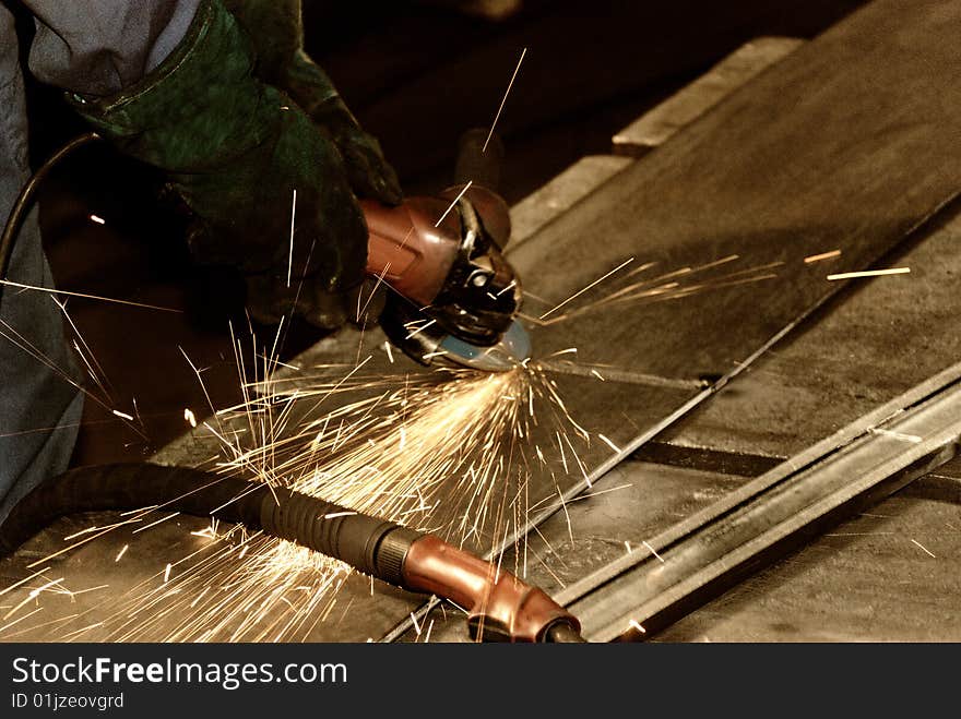 Worker grinding a big place of steel