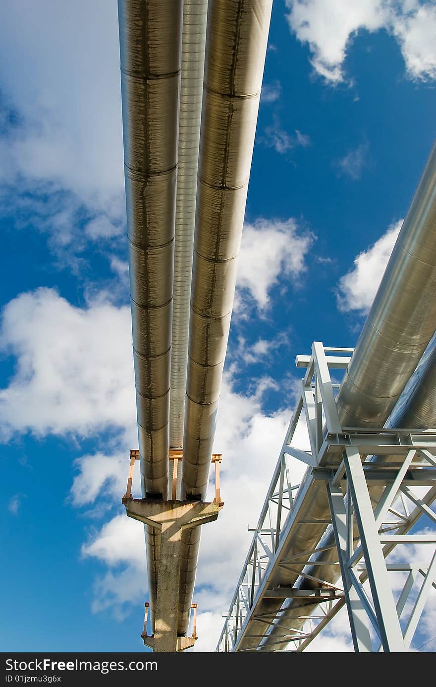 Industrial pipelines on pipe-bridge against blue sky. Industrial pipelines on pipe-bridge against blue sky.