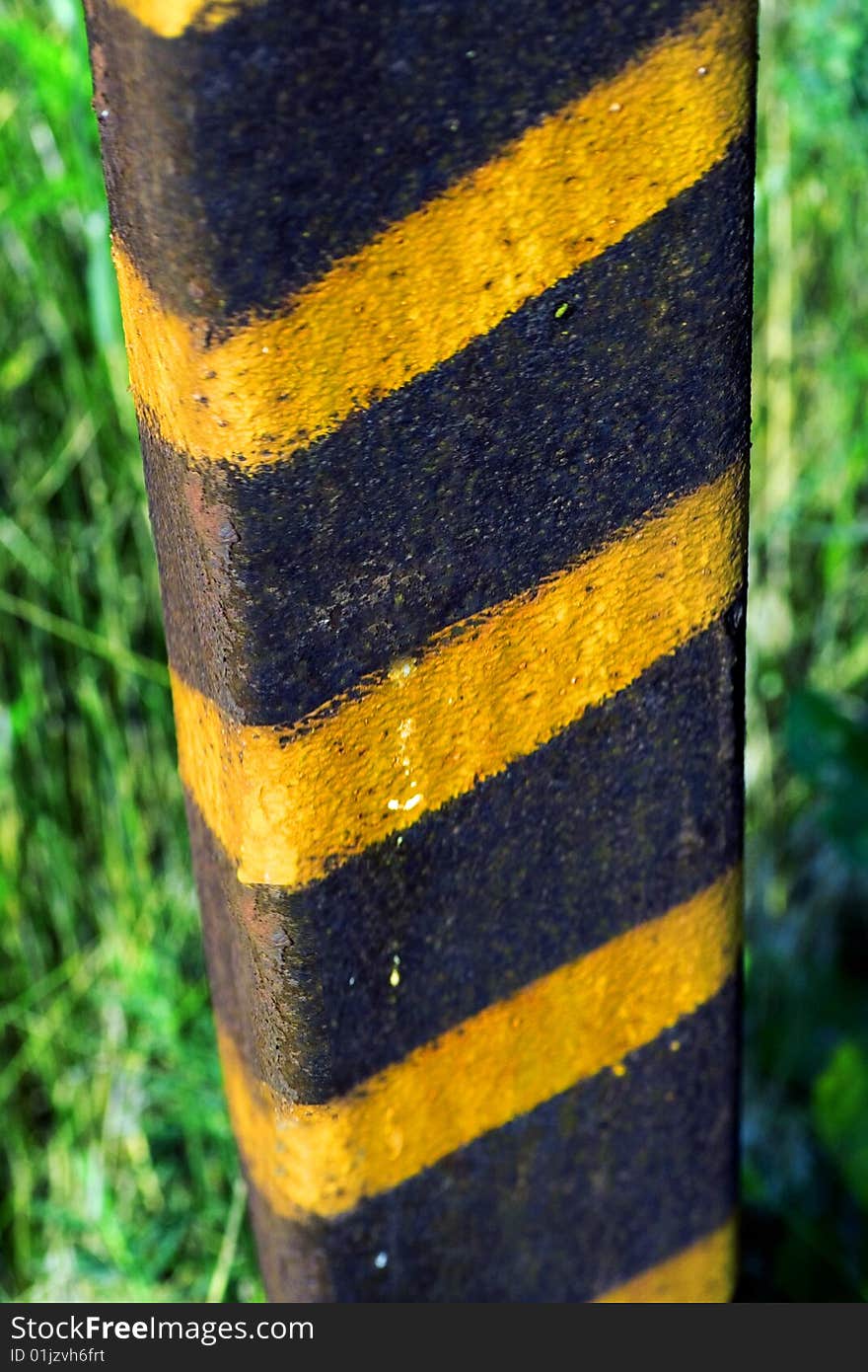 Green grass and old pole with grungy yellow stripes