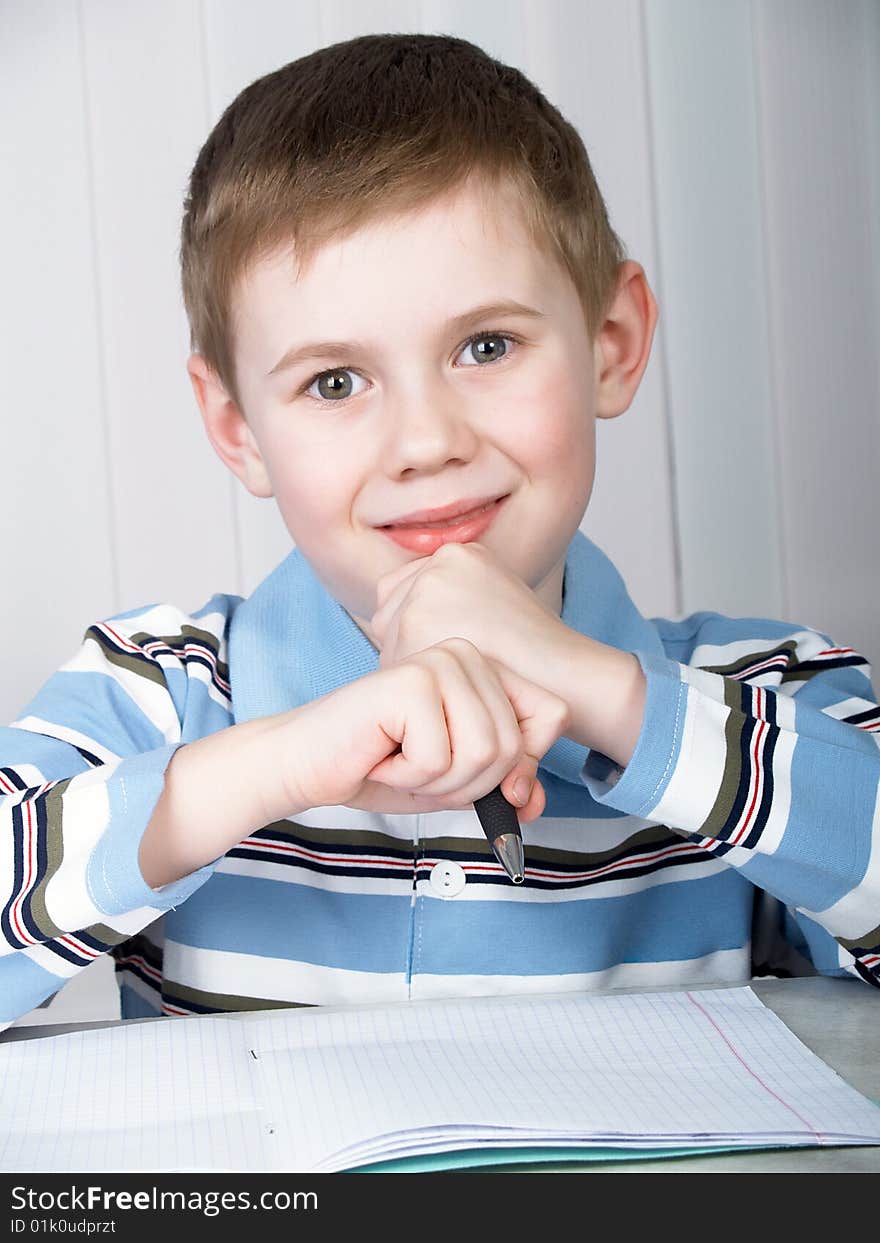 The litle boy doing homework on the table. The litle boy doing homework on the table