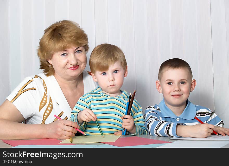 The grandmother with two grandsons is engaged behind a table. The grandmother with two grandsons is engaged behind a table