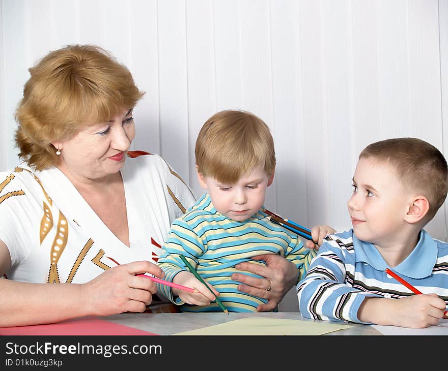 The grandmother with two grandsons is engaged behind a table. The grandmother with two grandsons is engaged behind a table