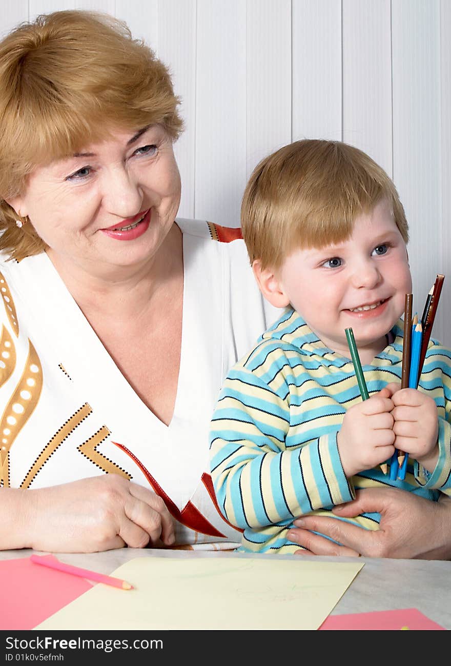 The grandmother with grandson is engaged behind a table. The grandmother with grandson is engaged behind a table