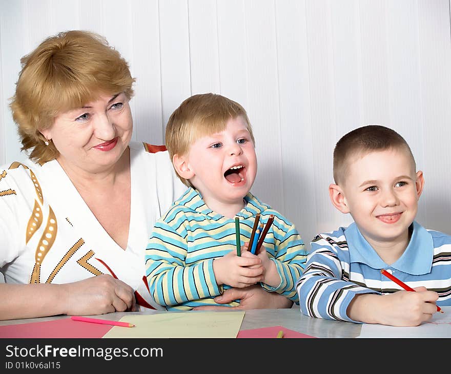 The grandmother with two grandsons is engaged behind a table. The grandmother with two grandsons is engaged behind a table