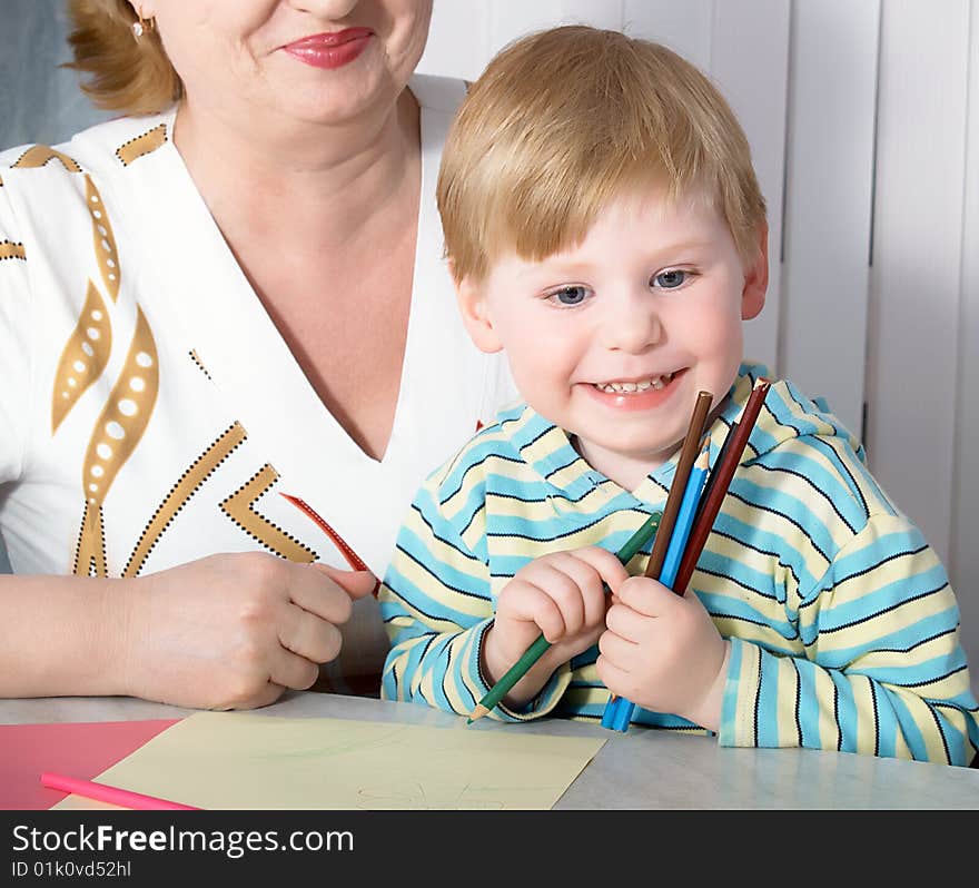 The grandmother with grandson is engaged behind a table. The grandmother with grandson is engaged behind a table