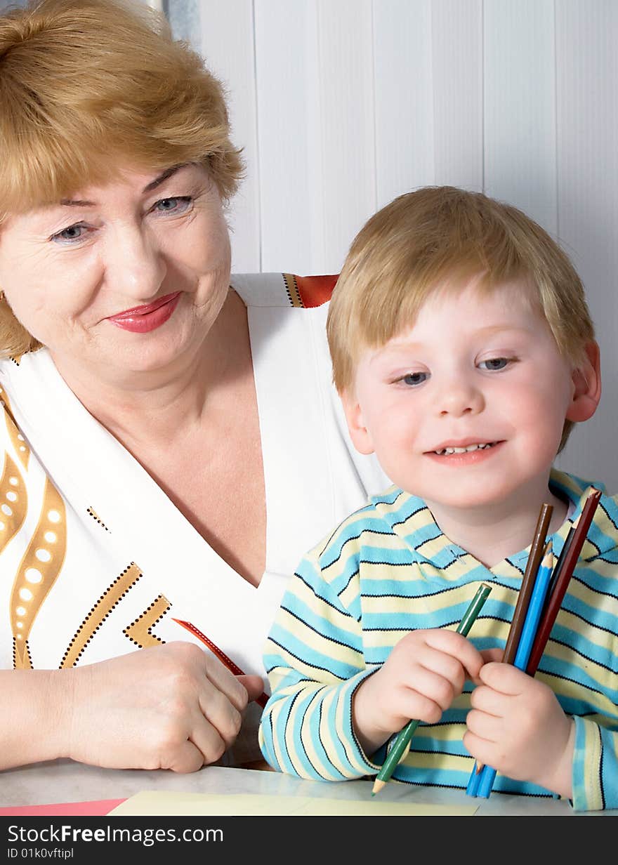 The grandmother with grandson is engaged behind a table. The grandmother with grandson is engaged behind a table