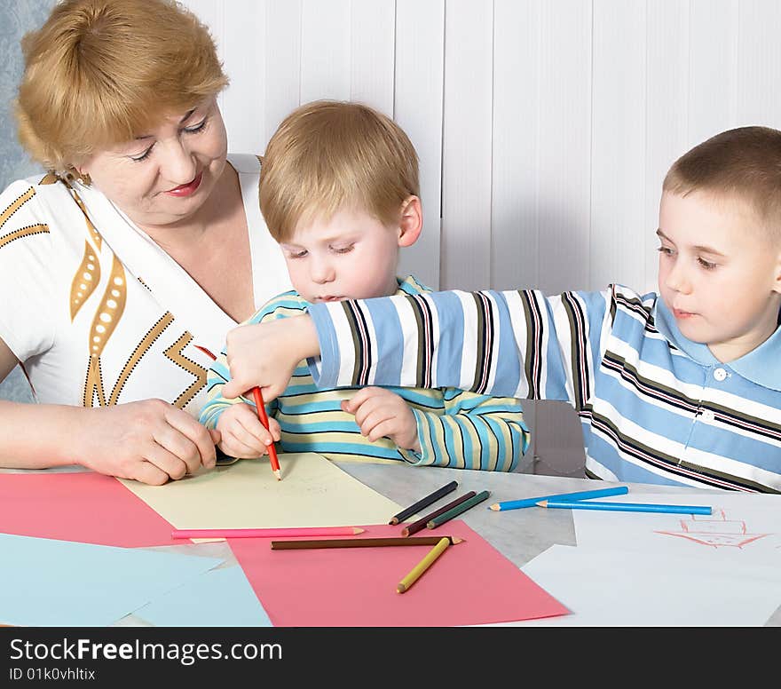 The grandmother with two grandsons is engaged behind a table. The grandmother with two grandsons is engaged behind a table