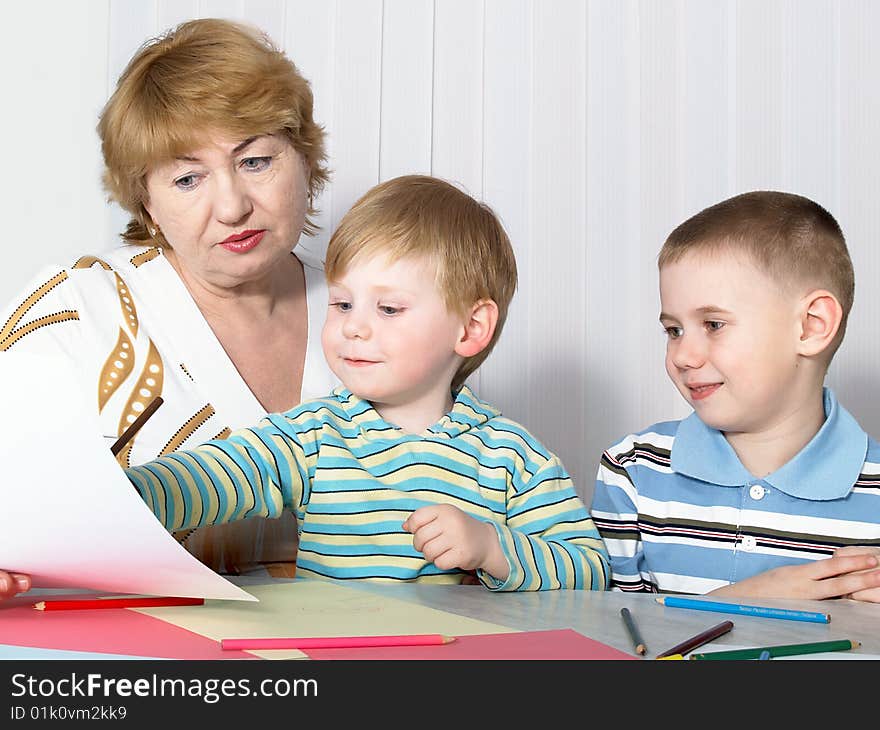 The grandmother with two grandsons is engaged behind a table. The grandmother with two grandsons is engaged behind a table