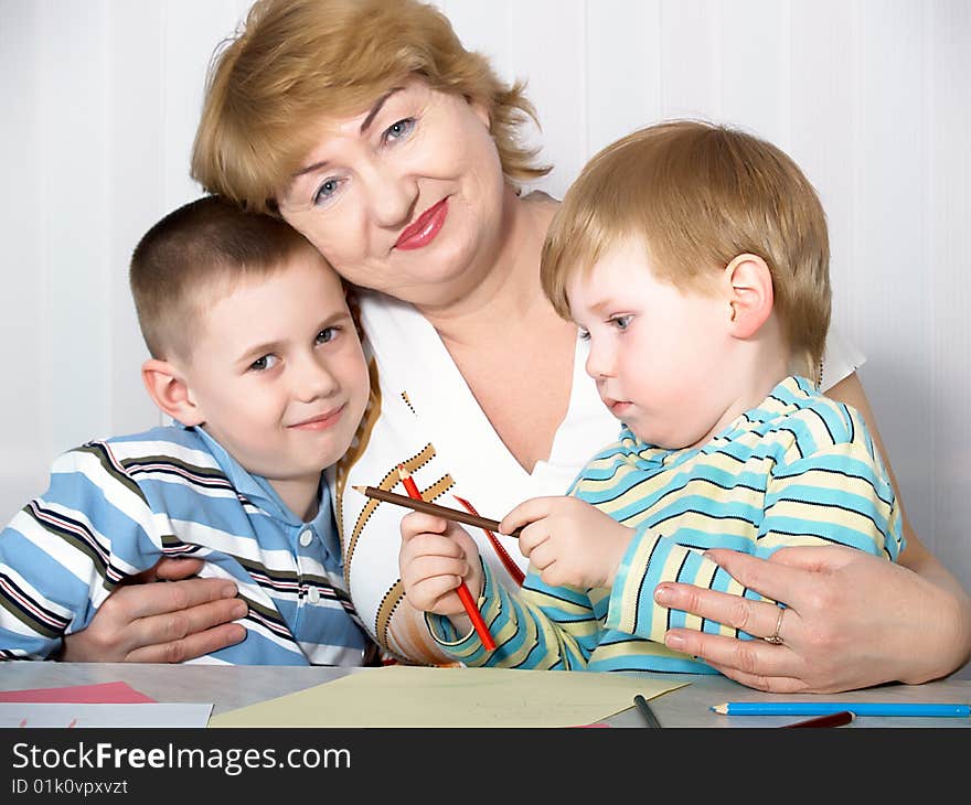 The grandmother with two grandsons is engaged behind a table. The grandmother with two grandsons is engaged behind a table