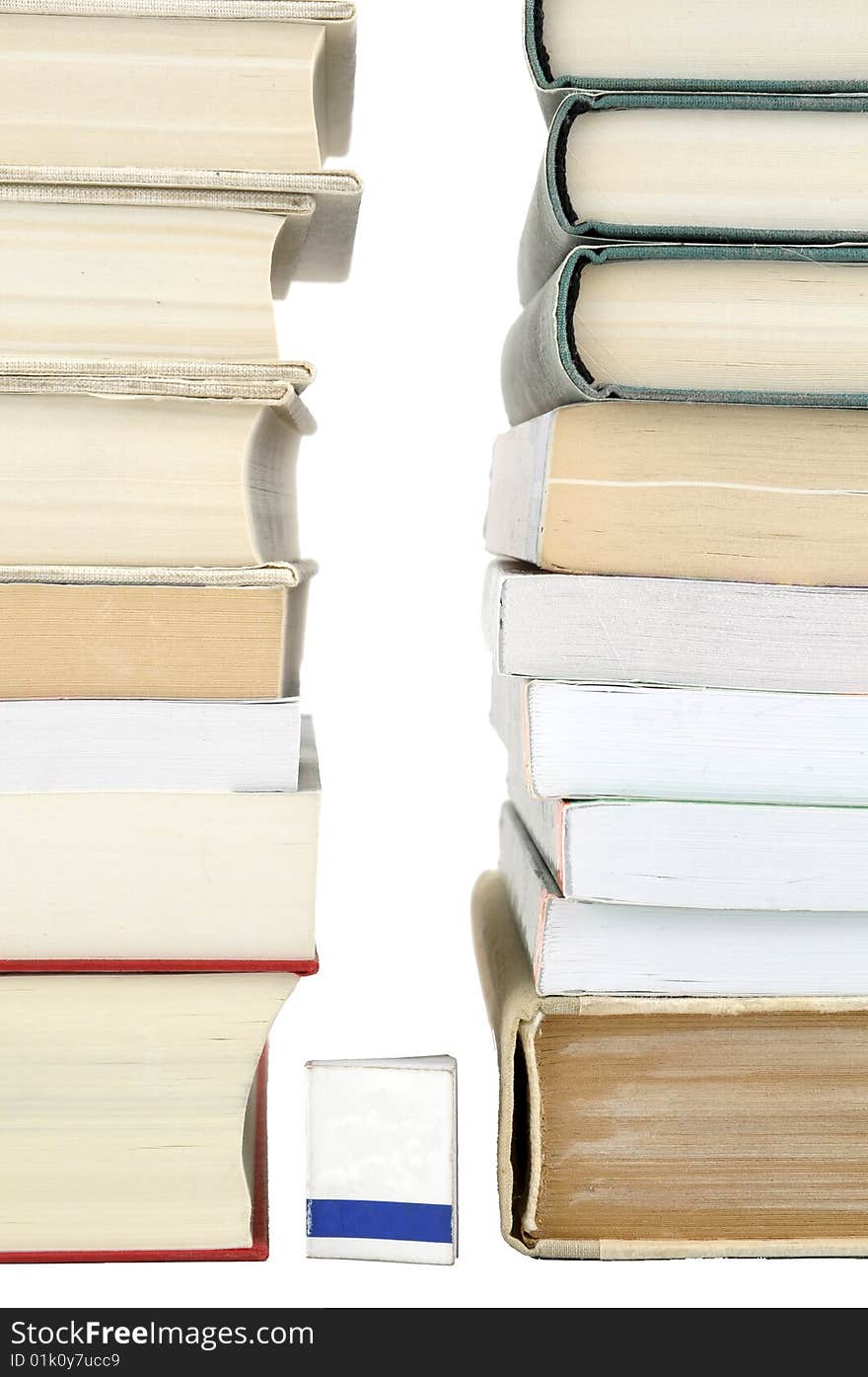 Small book between two stacks of books on white background