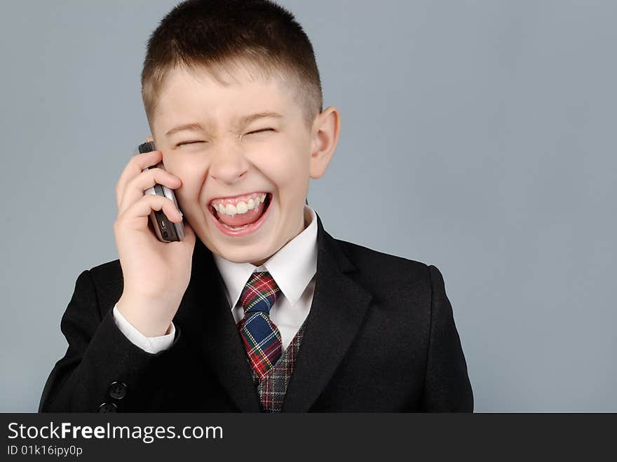 Laughing boy in a jacket with mobile phone