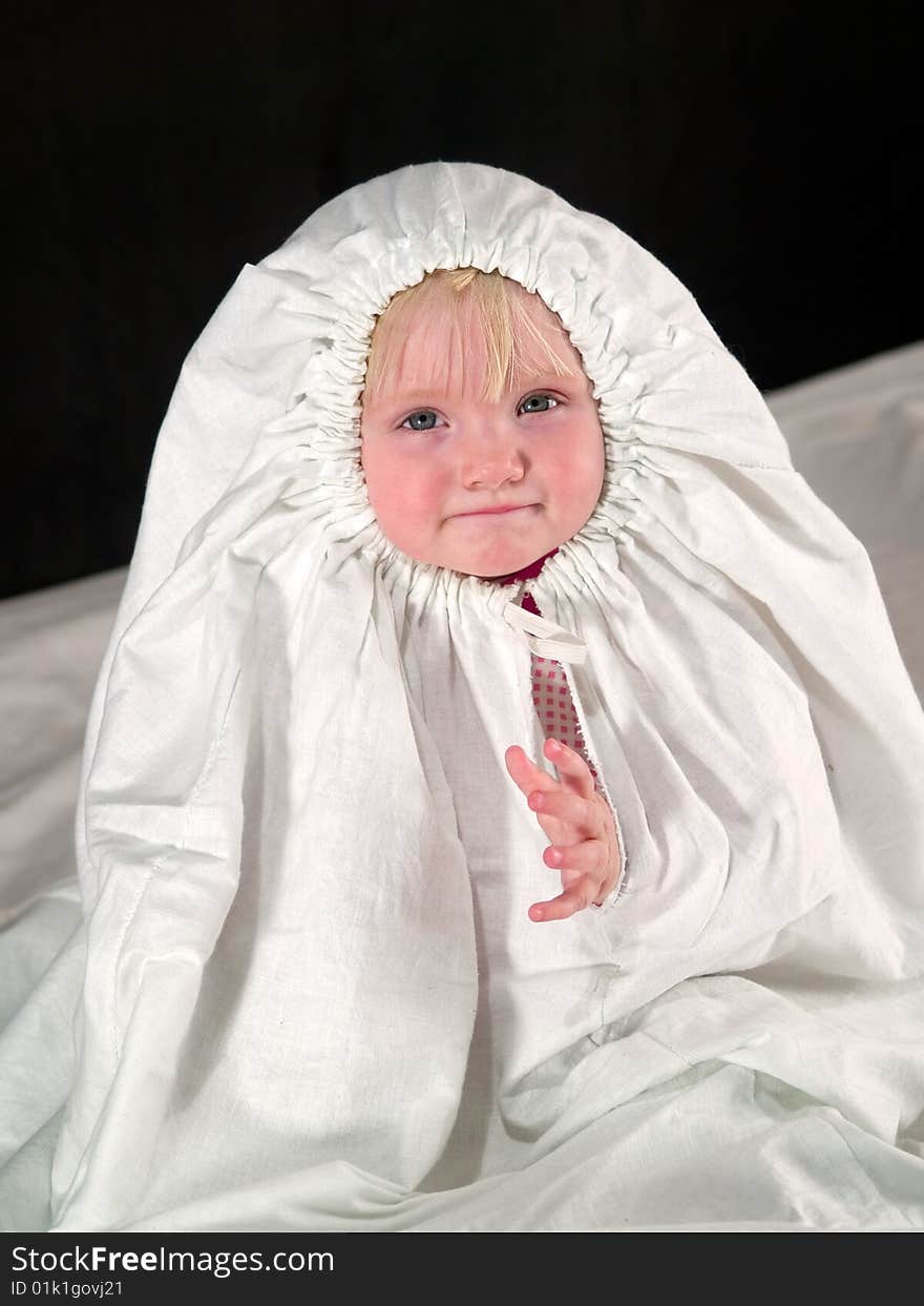 Child sits in white cloth and looking into camera