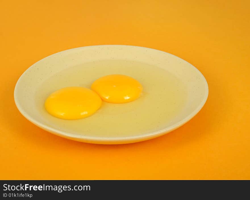 Two egg yolk in the dish, yellow background. Two egg yolk in the dish, yellow background