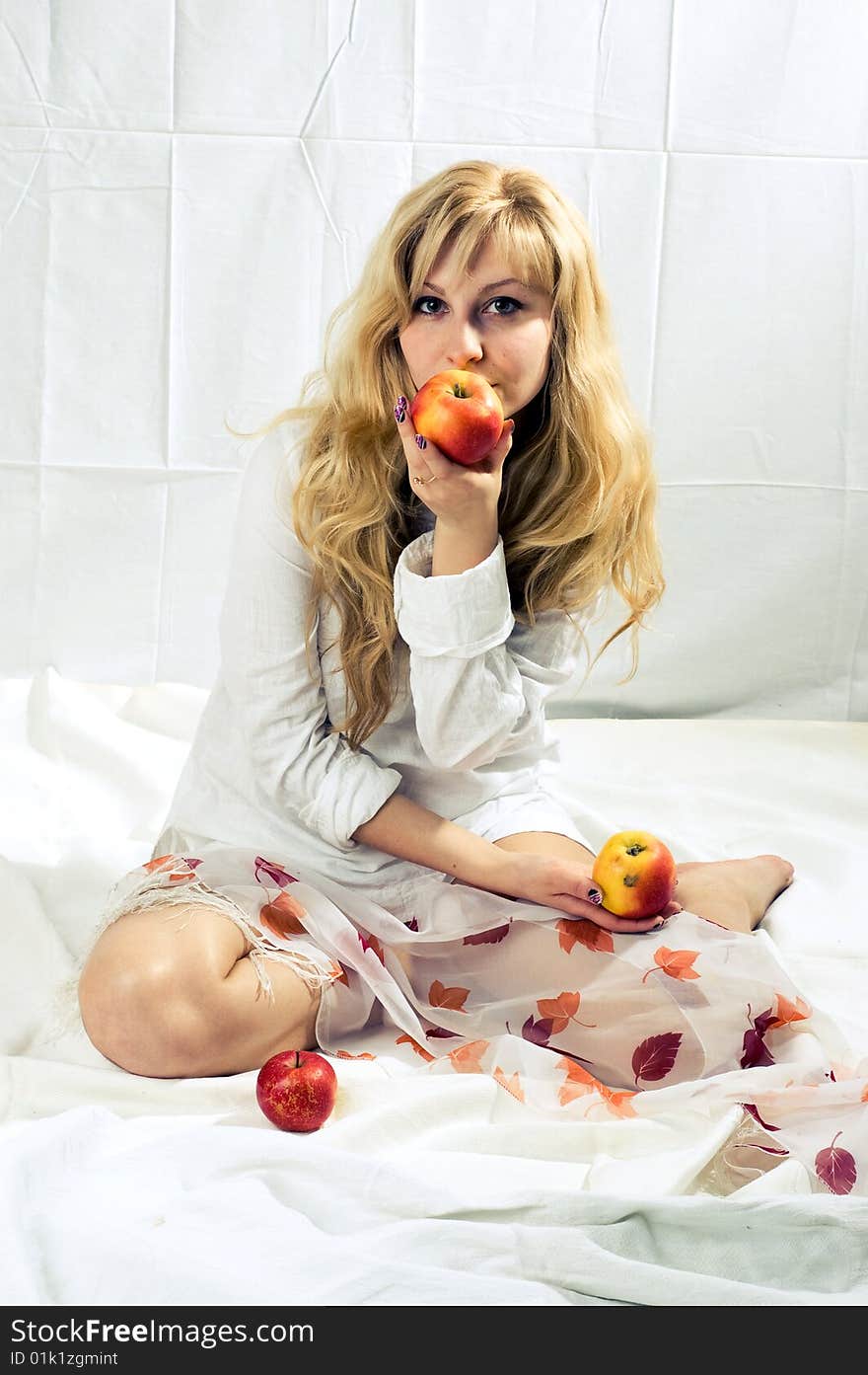 Portrait of a young blonde girl with apples in the white background