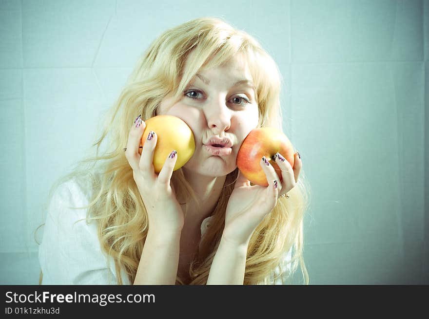 Portrait of a young blonde girl with apples in the white background