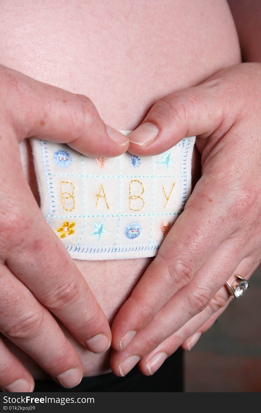 Heavily pregnant lady holding applique on her tummy. Heavily pregnant lady holding applique on her tummy