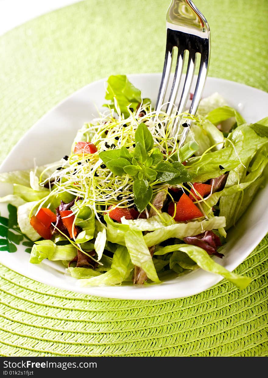 Fresh salad with fork and green cover