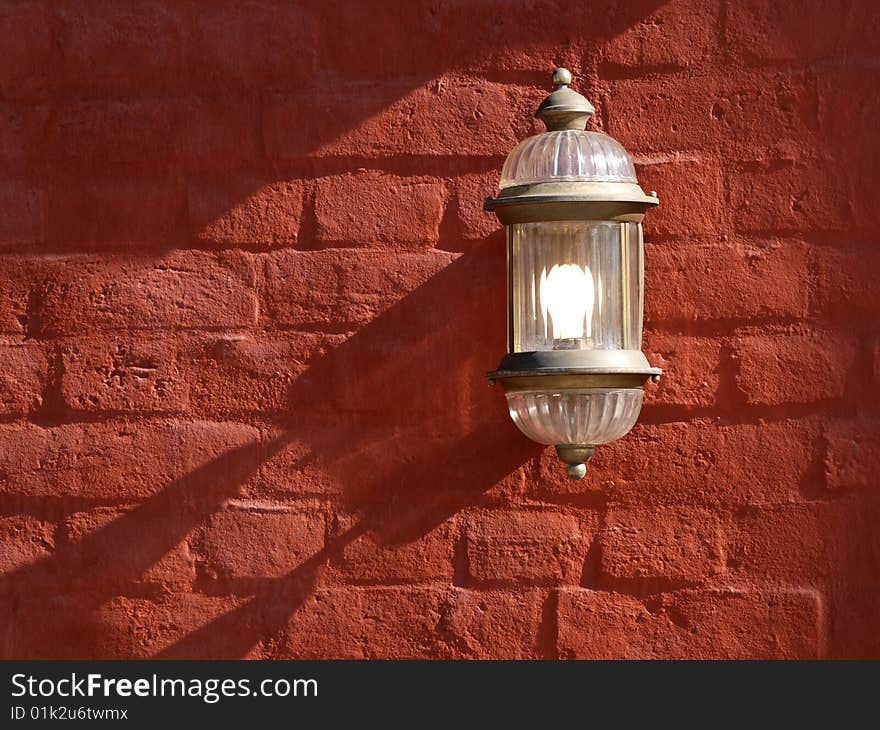 Color photo of red brick wall with an electric lamp