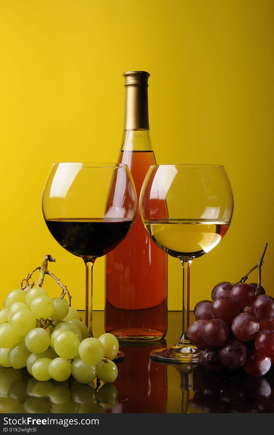 Two glasses and a bottle of wine with grapes