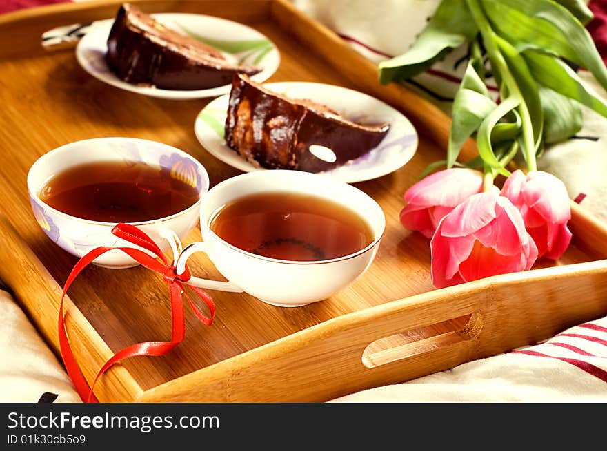 Breakfast tray on bed with tea, cakes and tulips. Breakfast tray on bed with tea, cakes and tulips