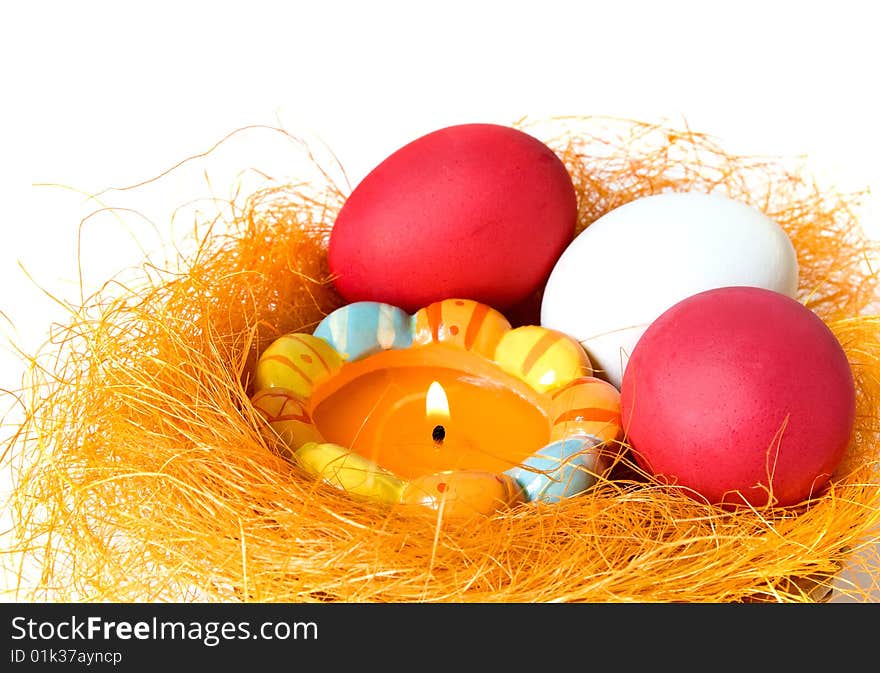 Eggs and candle in a small nest on white background