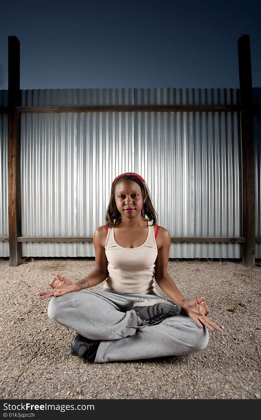 African-American woman meditating in front of corrugated metal