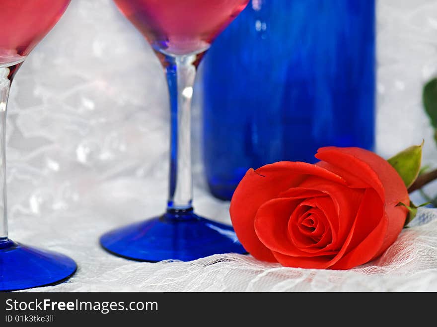 Bright rose with wine glasses and bottle on lace. Bright rose with wine glasses and bottle on lace.