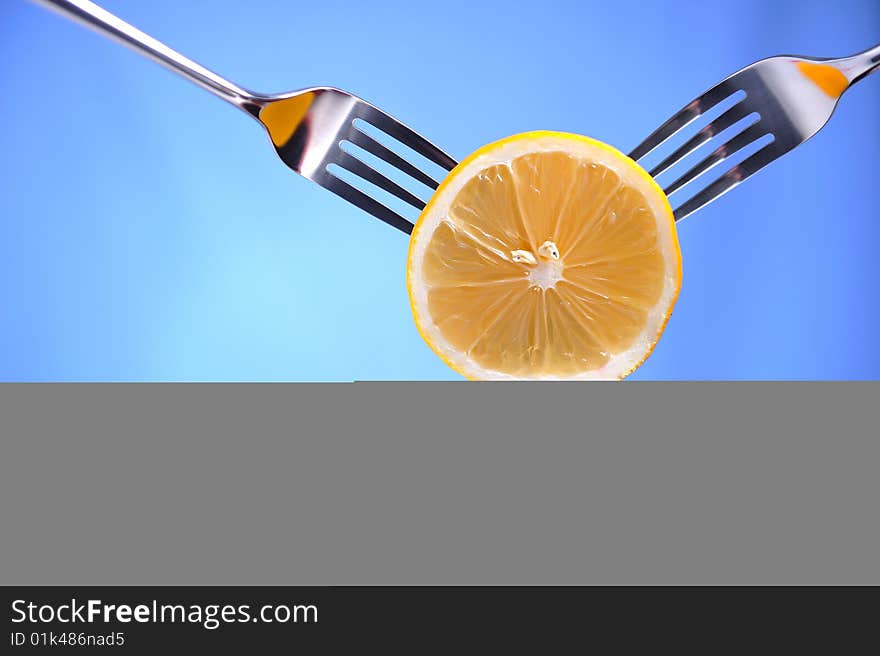 Three forks holding a lime, blue background. Three forks holding a lime, blue background