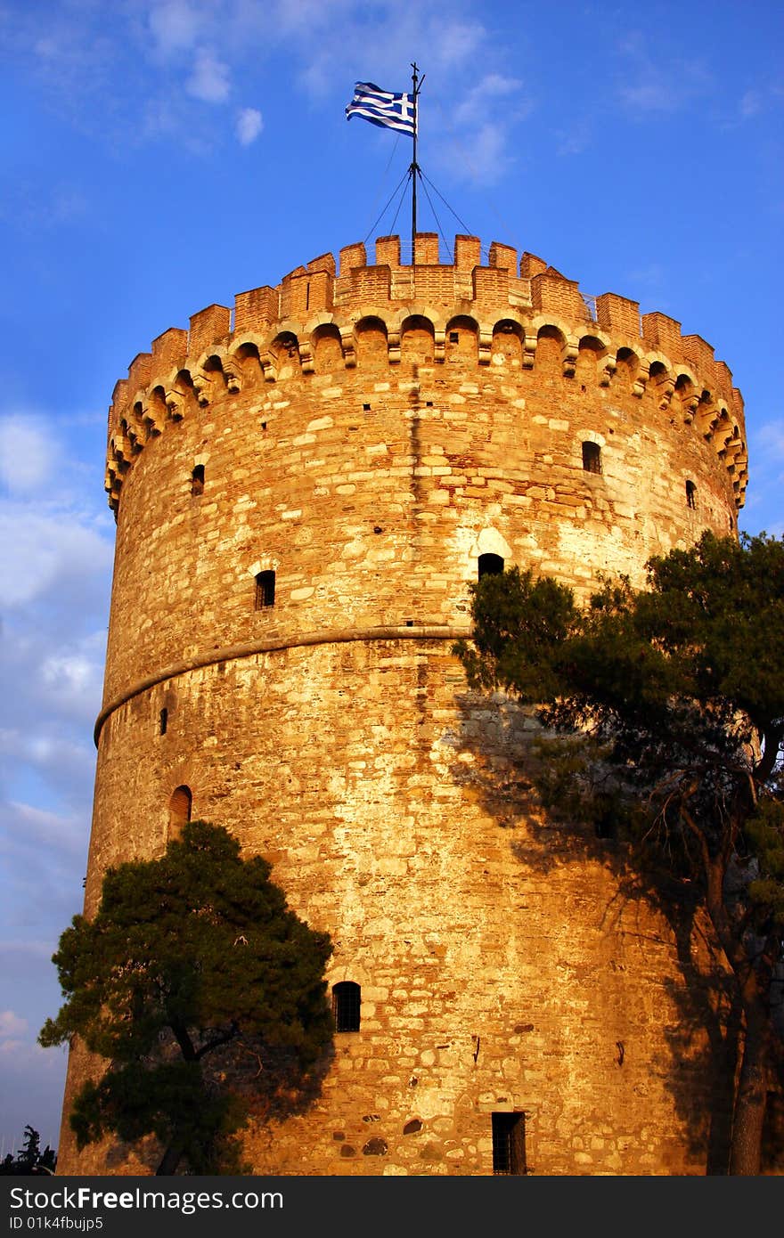 Ancient guard tower in Thessaloniki, Greece, known by the name of White Tower. Greek flag on top, clear sky. Ancient guard tower in Thessaloniki, Greece, known by the name of White Tower. Greek flag on top, clear sky.