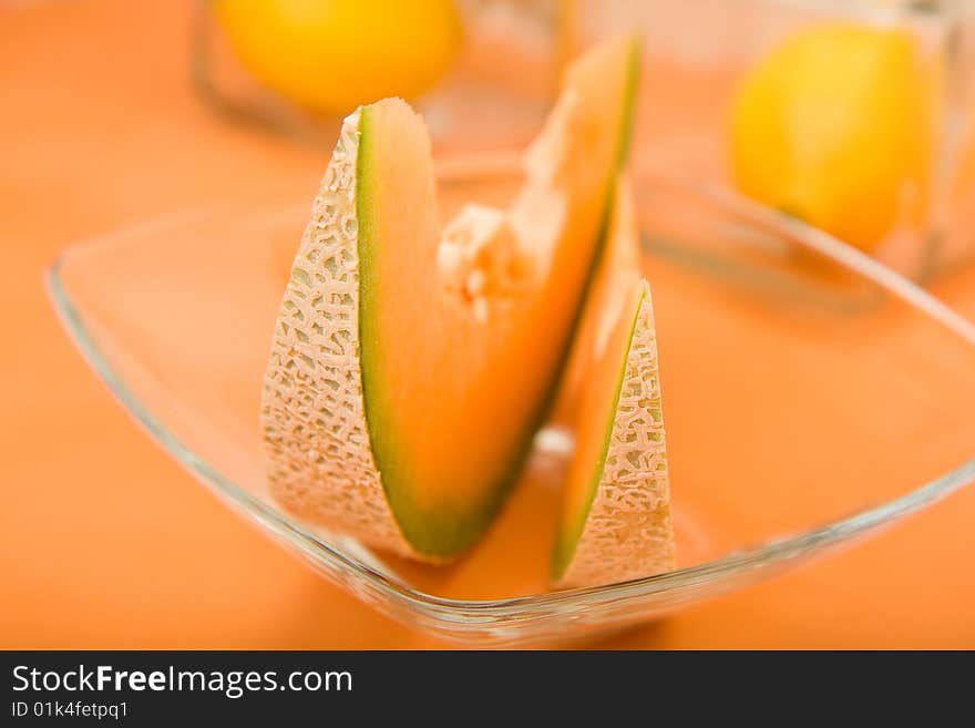 Cool cantaloupe melon wedges, ready for summer on orange in a glass bowl