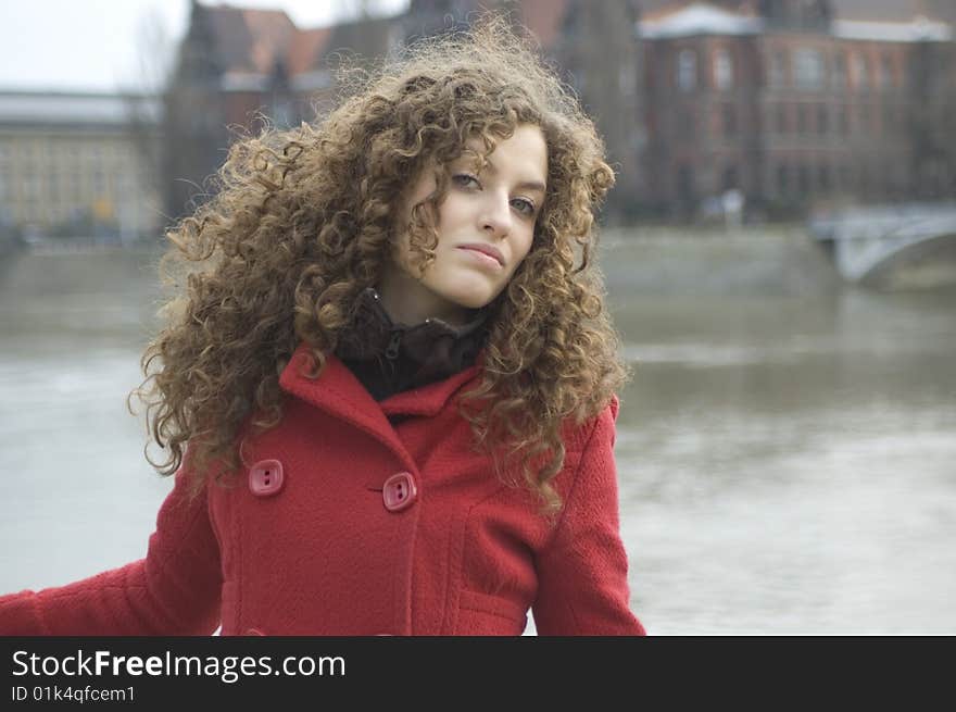 Teenage girl in Poland, portrait. Young girl with curly hairs wearing red coat, posing in Wroclaw city.
