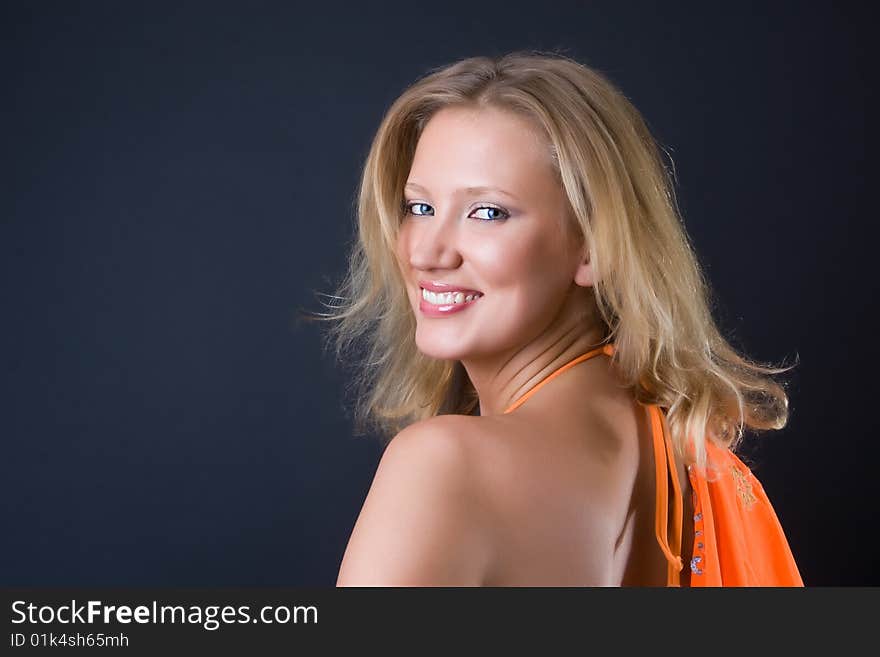 Beautiful girl in an orange bikini with a scarf against a dark background. Beautiful girl in an orange bikini with a scarf against a dark background