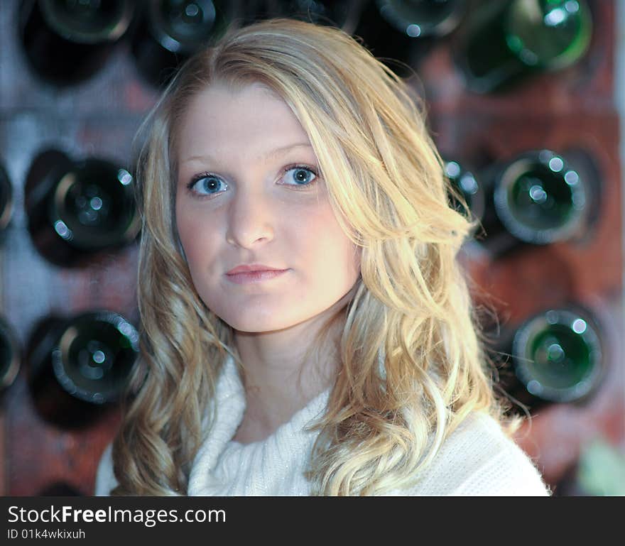 Attractive bond teen in front of wine rack. Attractive bond teen in front of wine rack