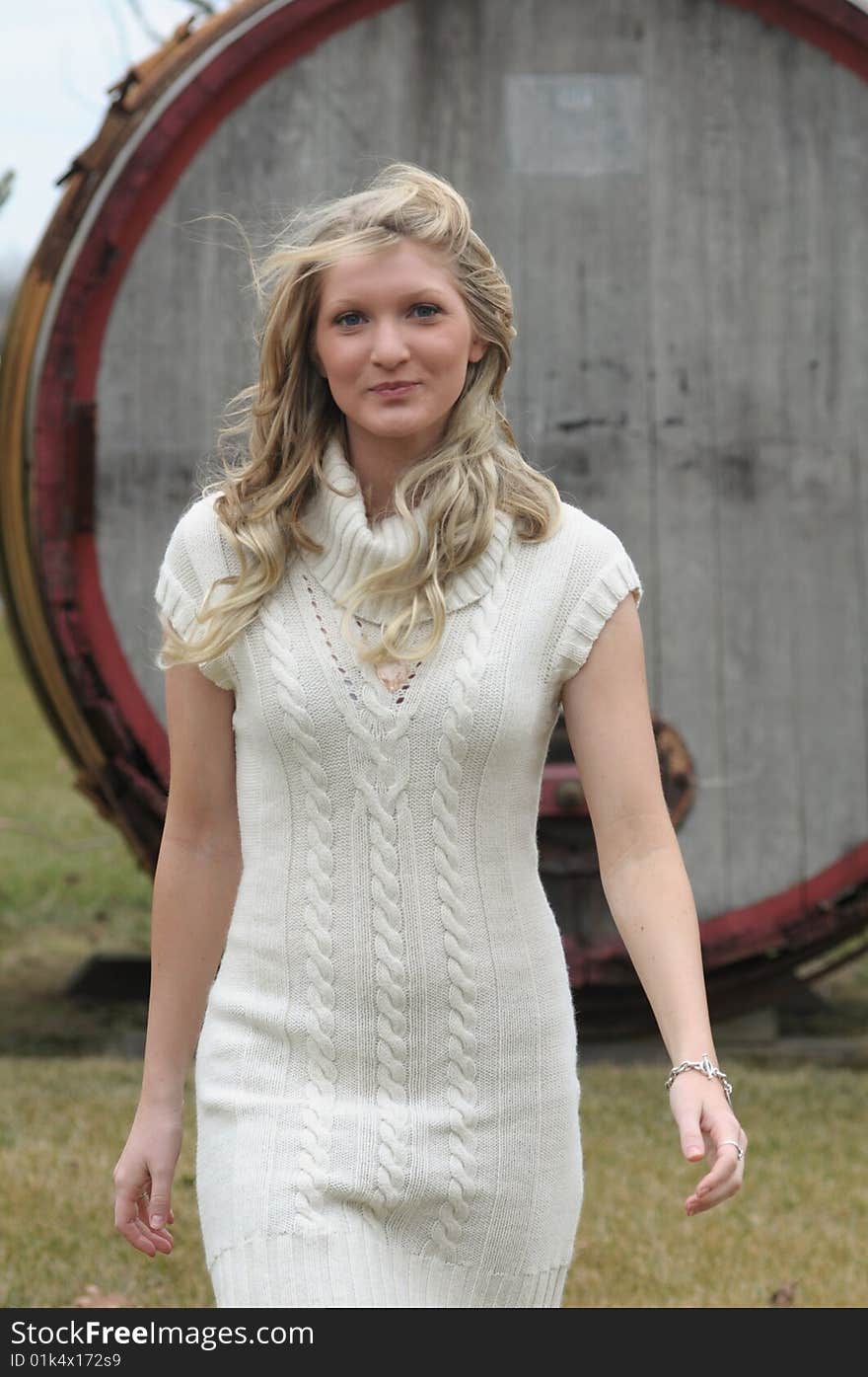 Attractive bond teen walking in sweater with barrel in background. Attractive bond teen walking in sweater with barrel in background