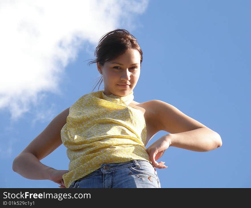 Girl in yellow clothes on a background blue sky with clouds