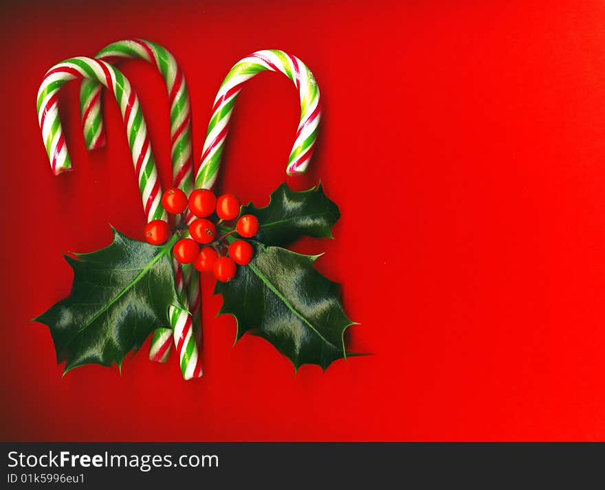 Candy cane with pretty holly leaves on red background, candy cane