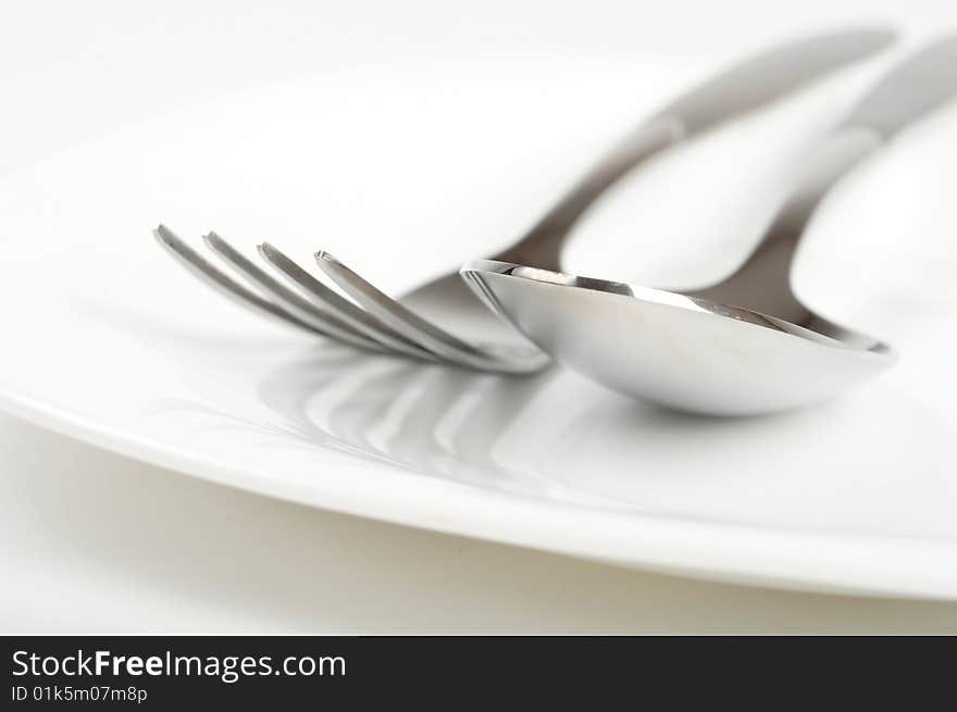 Photo of fork and spoon on white plate. Photo of fork and spoon on white plate