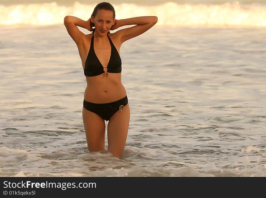 Woman bathes in ocean by the sunset