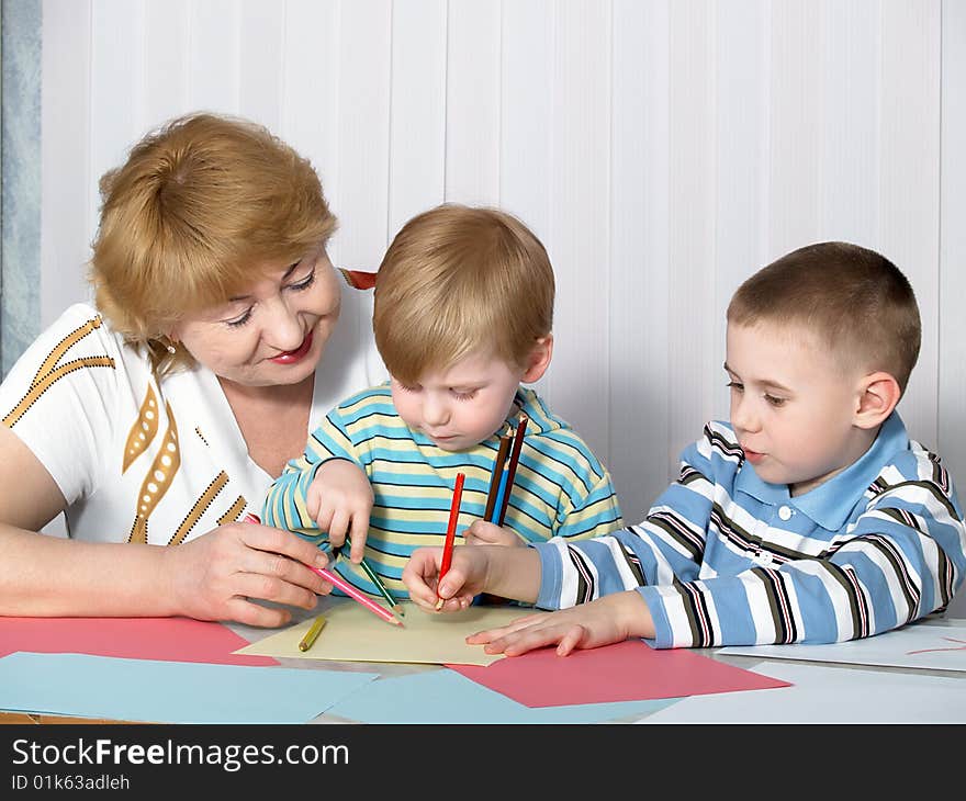 The grandmother is engaged in drawing with two grandsons. The grandmother is engaged in drawing with two grandsons